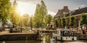 Boot langs een met bomen omzoomde smalle gracht in de zonsopgang bij Weesp. Rustig en gezellig dorp vol grachten en groen vlakbij Amsterdam.